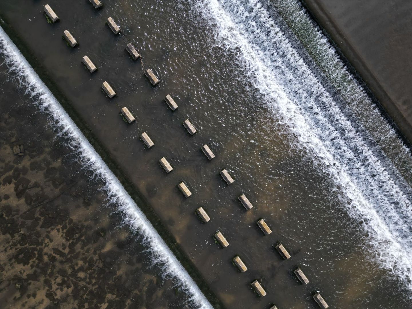 Aerial view of foaming river currents divided by concrete blocks
